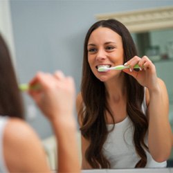 Woman with dental implants in Midwest City, OK brushing her teeth